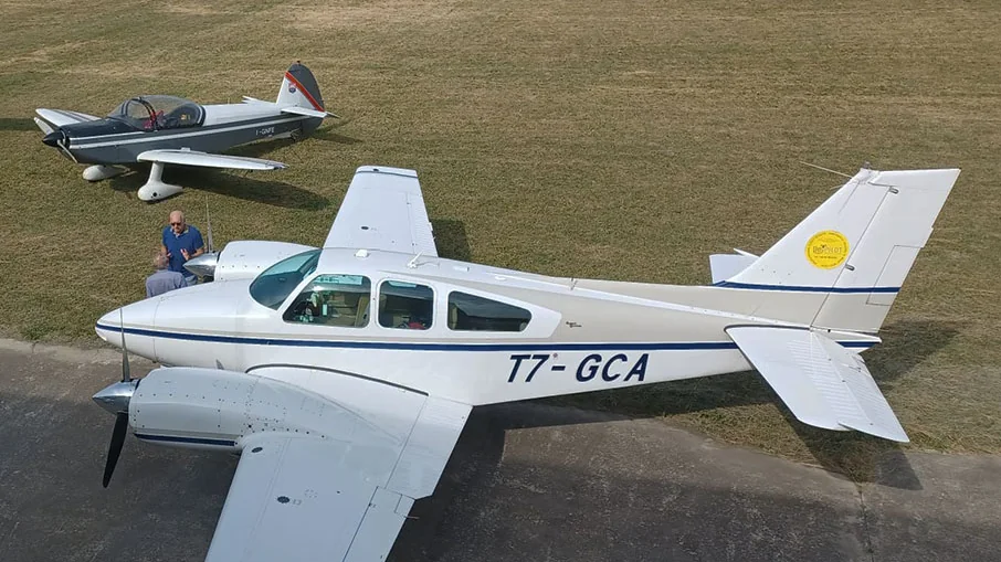 Light twin-engine aircraft parked on an airfield apron with a smaller aircraft behind it